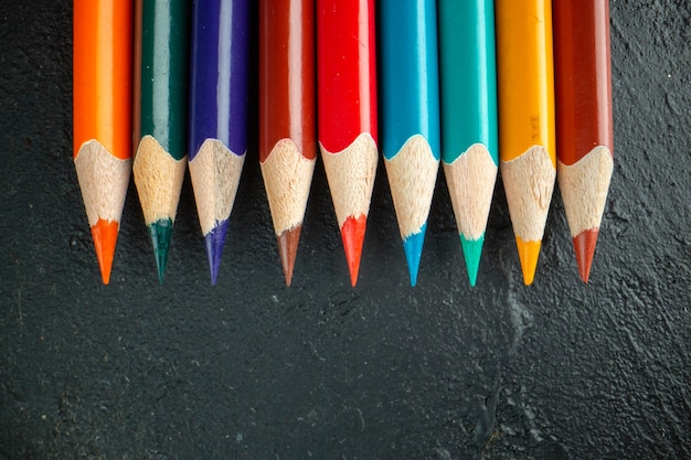 Top view colorful pencils lined on dark background