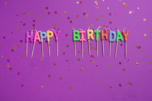 Free photo top view colorful word candles surrounded by golden confetti