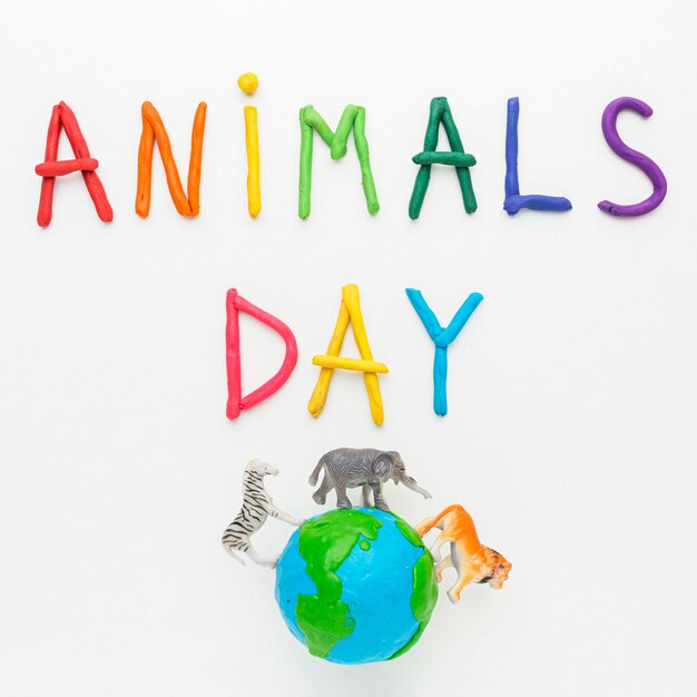 Top view of colorful writing and planet earth with animal figurines for animal day