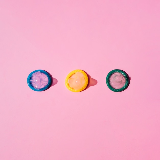 Top view coloured condoms on pink background