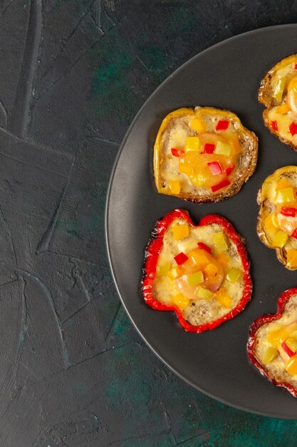 Free Photo top view cooked bell-peppers for lunch inside plate on dark-green surface