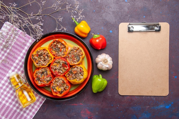 Top view cooked bell-peppers with ground meat and notepad on a dark surface meal vegetables food meat dolma