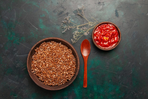 Free Photo top view cooked buckwheat with tomato sauce on the dark green surface