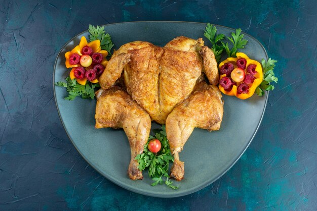 Top view cooked chicken with greens inside plate on the dark-blue desk chicken meat food dinner meat