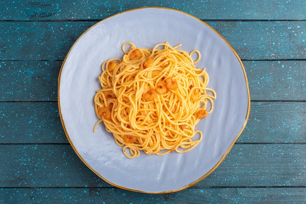 Top view of cooked italian pasta tasty inside blue plate on the blue wooden rustic surface