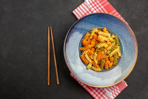 Top view cooked italian pasta unusual spiral pasta inside plate on dark space