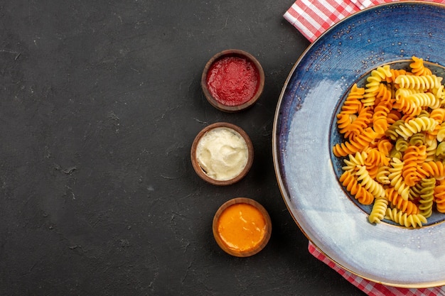 Free Photo top view cooked italian pasta unusual spiral pasta inside plate on dark space