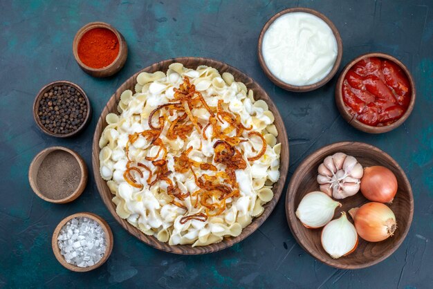 Top view cooked italian pasta with different seasonings on blue