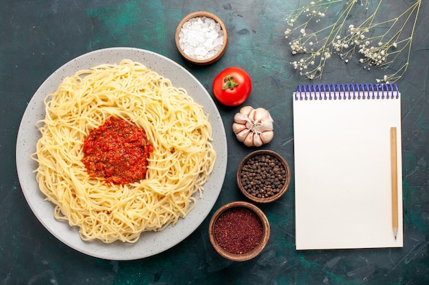 Free photo top view cooked italian pasta with minced meat tomato sauce and seasonings on blue desk