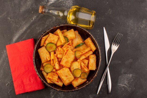 A top view cooked italian pasta with tomato sauce and cucumber inside pan