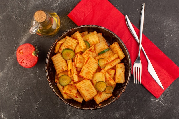 A top view cooked italian pasta with tomato sauce and cucumber inside pan