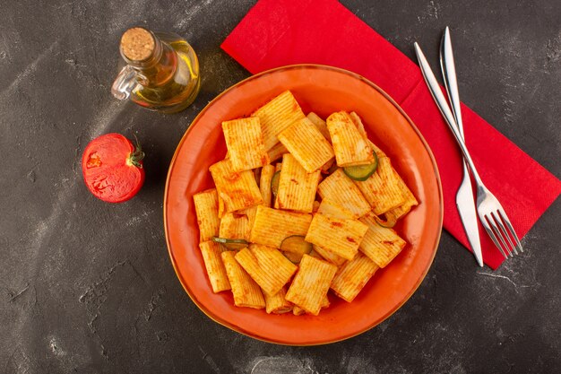 A top view cooked italian pasta with tomato sauce and cucumber inside plate