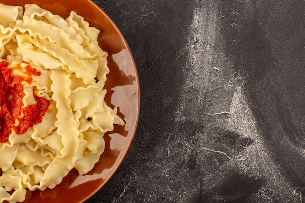 A top view cooked italian pasta with tomato sauce inside plate