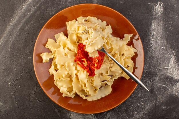 A top view cooked italian pasta with tomato sauce inside plate