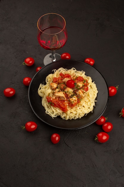 Free photo top view cooked pasta with chicken wings and tomato sauce inside black plate on the dark floor