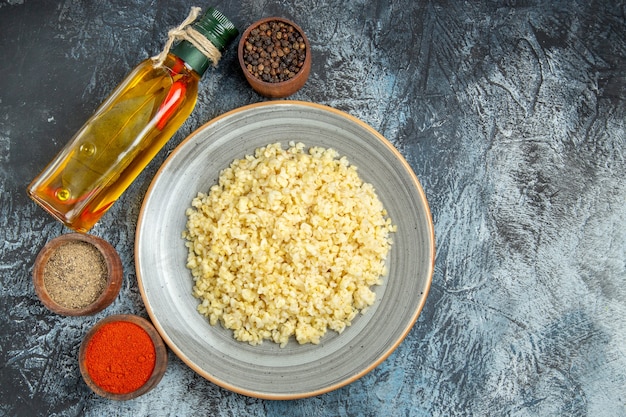 Top view of cooked pearl barley with seasonings on a light surface