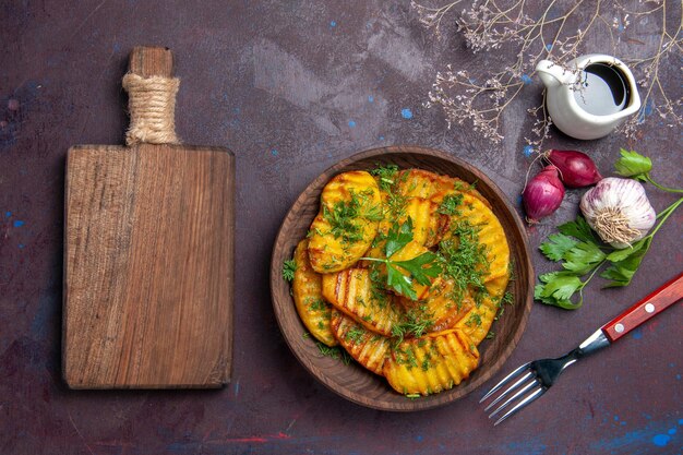 Top view cooked potatoes delicious dish with greens on a dark surface cooking meal dish potato dinner