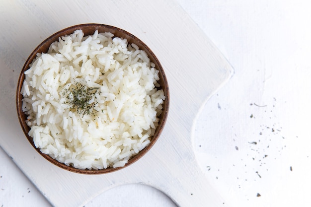 Free Photo top view of cooked rice tasty meal inside brown pot with pepper on the white surface