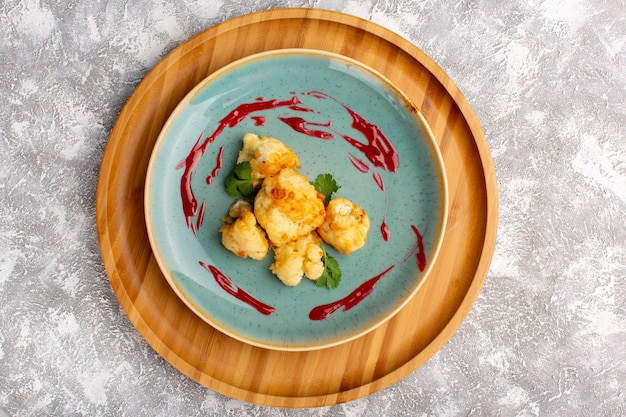 Top view of cooked sliced cauliflower inside plate on light-white surface