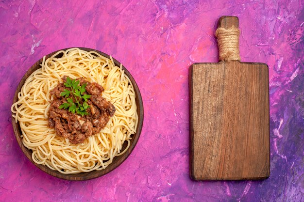 Top view cooked spaghetti with ground meat on pink floor dough meal pasta dish