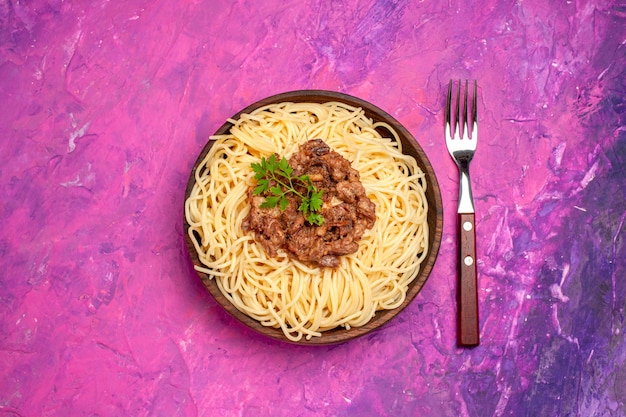 Top view cooked spaghetti with ground meat on pink table color dish dough pasta