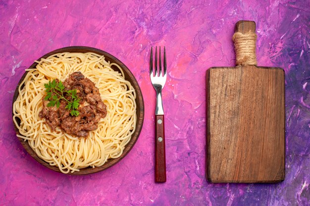 Top view cooked spaghetti with ground meat on pink table color dough pasta