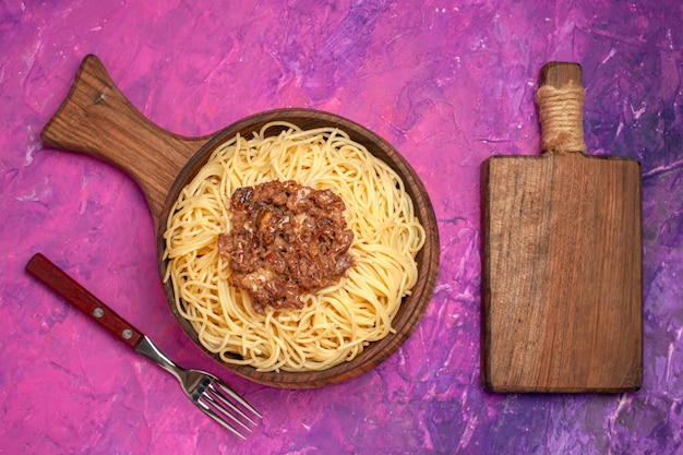 Free photo top view cooked spaghetti with ground meat on the pink table pasta dough dish seasoning