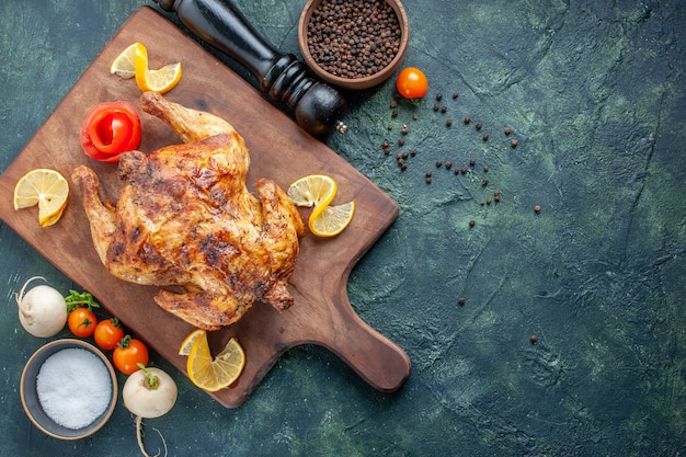 Top view cooked spiced chicken with lemon slices on dark surface