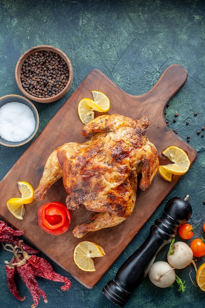 Free photo top view cooked spiced chicken with lemon slices on dark surface