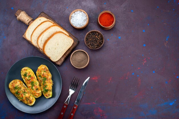 Top view cooked tasty squashes with seasonings and bread loafs on dark purple desk.