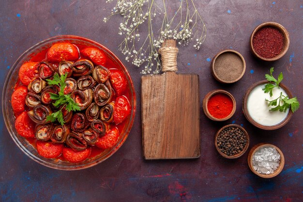 Top view cooked vegetable meal delicious tomatoes and eggplants with seasonings on dark surface