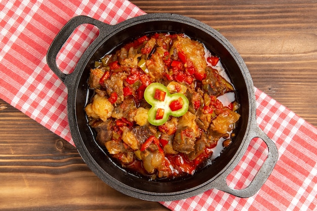 Top view cooked vegetable meal including vegetables and meat inside on wooden brown desk