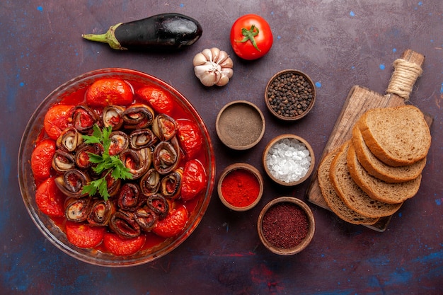 Top view cooked vegetable meal tomatoes and eggplants with seasonings bread on dark surface