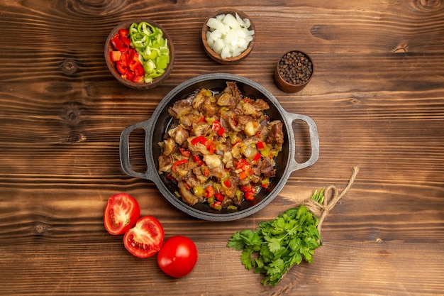 Top view cooked vegetable meal with meat and fresh sliced bell-pepper on wooden brown desk