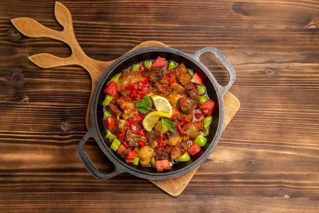 Free photo top view cooked vegetable meal with meat and sliced bell-peppers inside pan on brown wooden surface