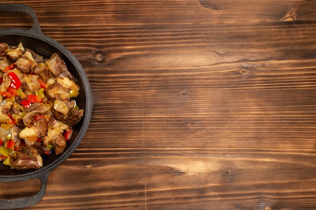 Top view cooked vegetable meal with meat and sliced bell peppers on the wooden desk