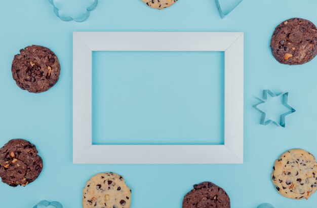 Top view of cookies around frame on blue background with copy space