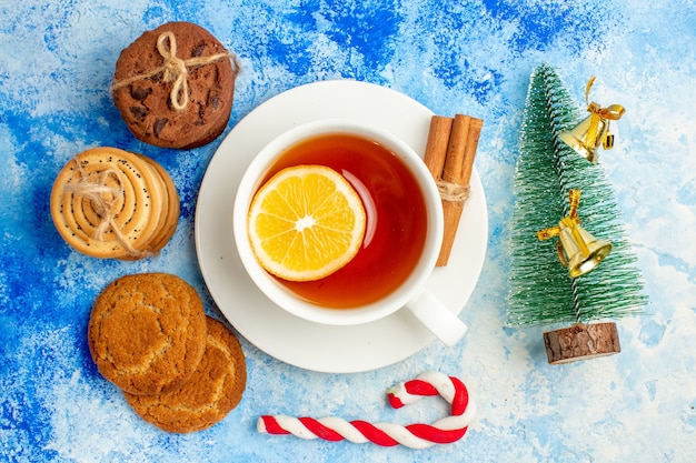 Top view cookies tied up with rope cup of tea small xmas tree on blue table