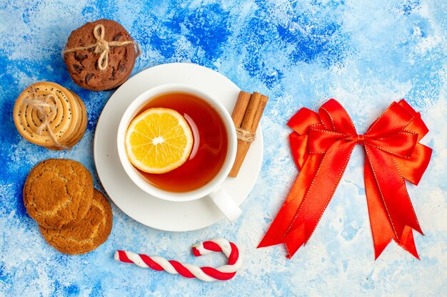 Top view cookies tied up with rope red bow cup of tea on blue table