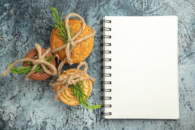 Top view cookies tied with ropes notepad on grey surface