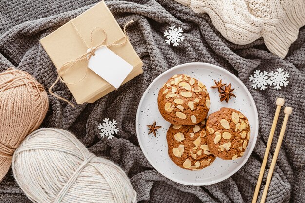 Top view cookies, yarn and gift box on blanket