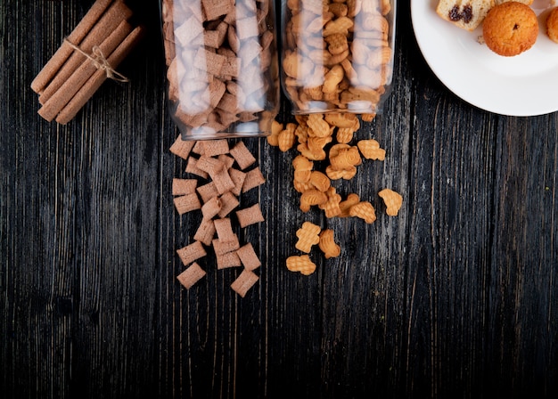 Free Photo top view copy space cookies in a jar of cornflakes and corn sticks on a black wooden background