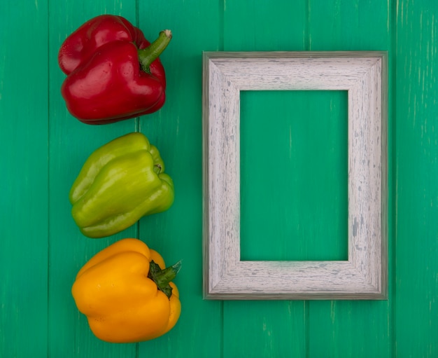 Top view  copy space gray frame with colored bell peppers on a green background