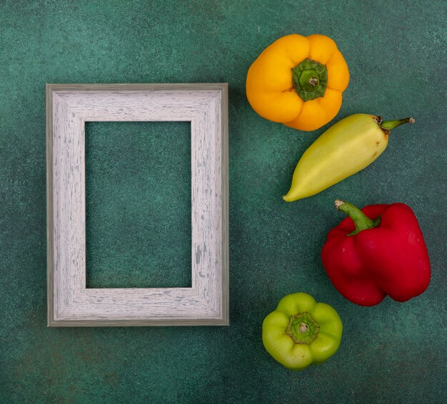 Top view  copy space gray frame with colored bell peppers on green background