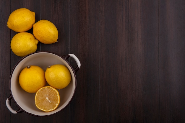 Top view  copy space lemons in white saucepan on wooden background