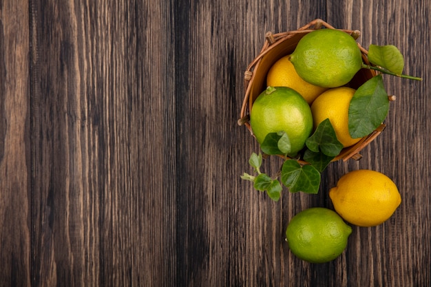 Top view  copy space limes with lemons in a basket on wooden background