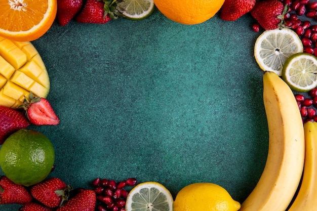 Top view  copy space mix of fruits mango  banana  strawberries  lemon  orange with frame on a green background