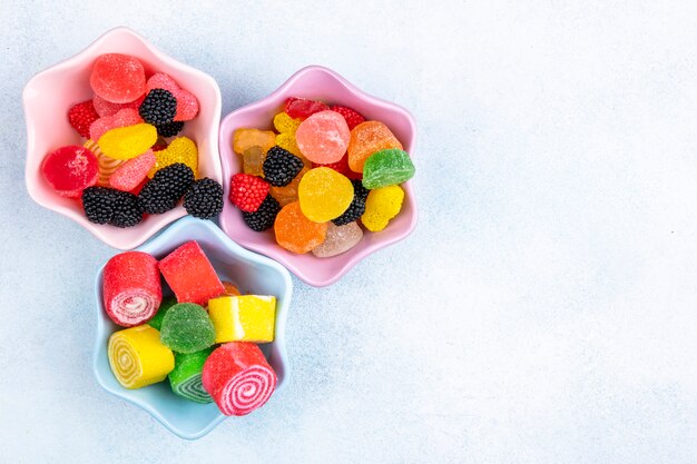 Top view copy space multi-colored marmalades in a jam outlet on a white background