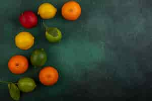 Free photo top view  copy space peach with lemons  limes and oranges on a green background