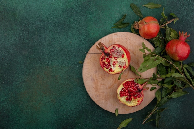 Free photo top view  copy space pomegranates with twigs on a stand on a green background